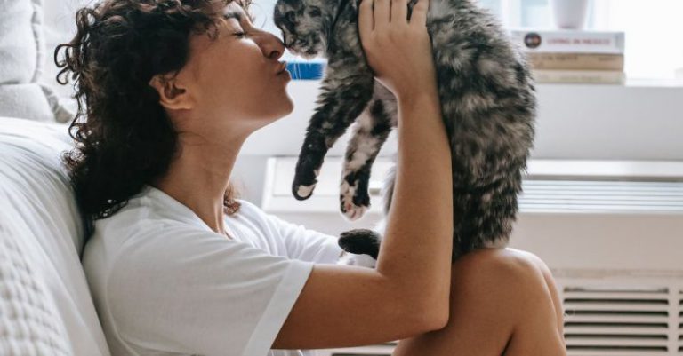 Pets Love - Charming woman kissing cute cat in bedroom