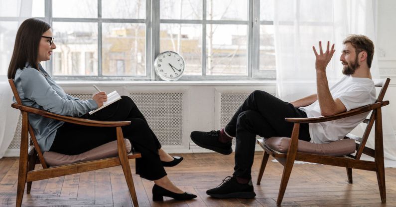 Mental Health Ribbon - Person in Black Pants and Black Shoes Sitting on Brown Wooden Chair