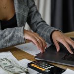 Budget Calculator - A Woman in Plaid Blazer Using Her Laptop