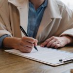 Brief Document - Focused woman writing in clipboard while hiring candidate