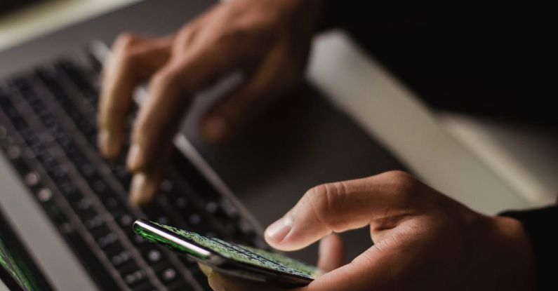 Software Selection - Crop faceless person using laptop and smartphone in darkness