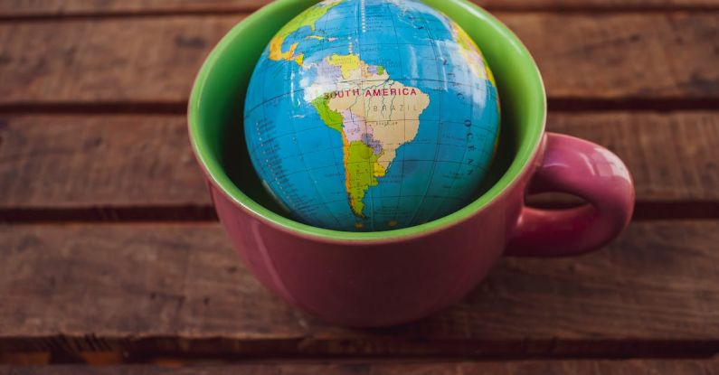 Facemask Globe - A small globe sitting in a cup on a wooden table