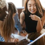 Contract Management - Multiethnic cheerful colleagues talking about job and working with documents