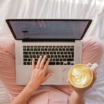 Blogging - person using MacBook Pro and holding cappuccino