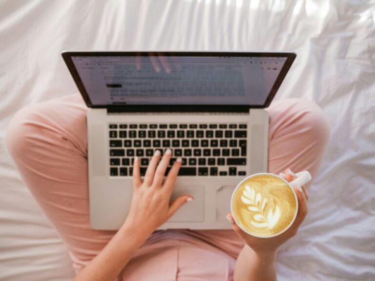 Blogging - person using MacBook Pro and holding cappuccino