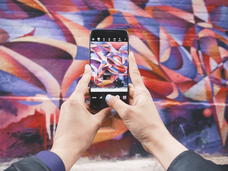 Influencer - person holding Android smartphone and taking a photo of abstract wall during daytime
