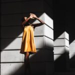 Influencers - woman in orange dress and standing near white post