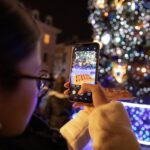 Influencers - person holding iphone taking photo of lighted christmas tree