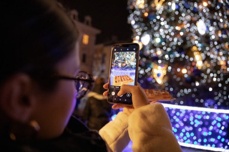 Influencers - person holding iphone taking photo of lighted christmas tree