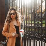 Influencers - woman in brown coat holding white cup