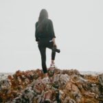Influencers - woman in black jacket standing on brown rocky mountain during daytime