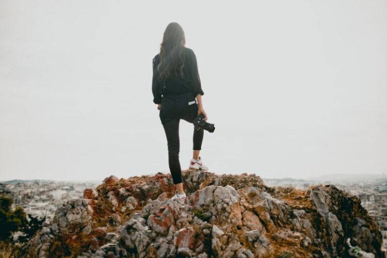 Influencers - woman in black jacket standing on brown rocky mountain during daytime