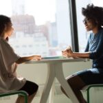 Interview - two women sitting beside table and talking