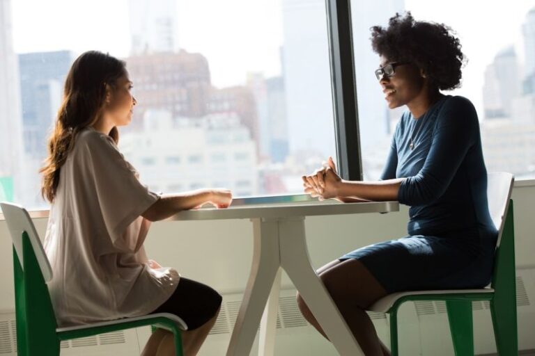 Interview - two women sitting beside table and talking