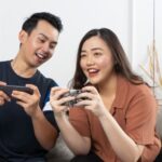 Entertainment Digital - a man and woman sitting on a couch looking at a cell phone