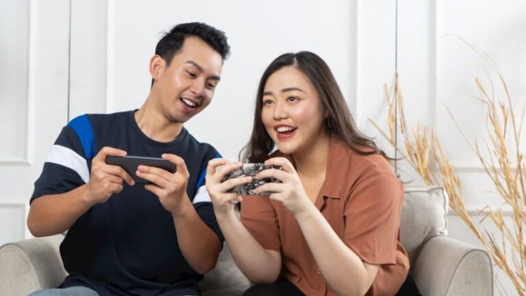 Entertainment Digital - a man and woman sitting on a couch looking at a cell phone